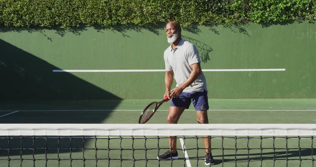 African american senior man playing tennis on the tennis court on a bright sunny day. retirement sports and active senior lifestyle.
