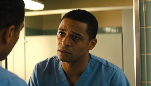 Healthcare worker checking mirror in restroom, wearing blue scrubs, introspective closeup