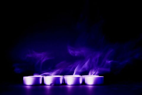 Serene purple smoke from tealight candles in darkness