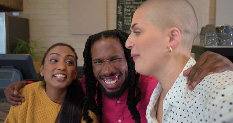 Diverse friends laughing and hugging at cozy urban cafe counter over espresso cups