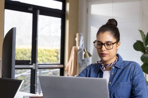 Young professional working on laptop in bright modern office by window