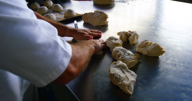 Depicts baker kneading fresh dough on counter. Ideal for content related to baking, culinary arts, homemade bread, artisanal bakeries, and small-scale food production.