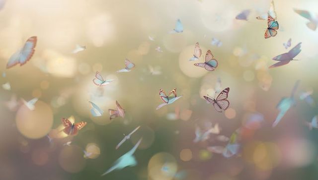 Pastel butterflies fluttering through sunlit bokeh meadow creating ethereal dreamy scene