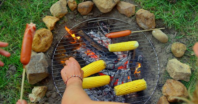 High angle view of friends roasting hot dog and corn on campfire - Download Free Stock Photos Pikwizard.com