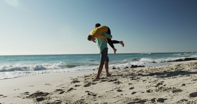 Couple playing together on sandy beach under clear blue sky - Download Free Stock Images Pikwizard.com