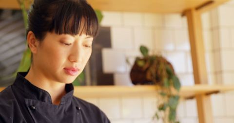Focused Asian Female Chef Working in Modern Kitchen