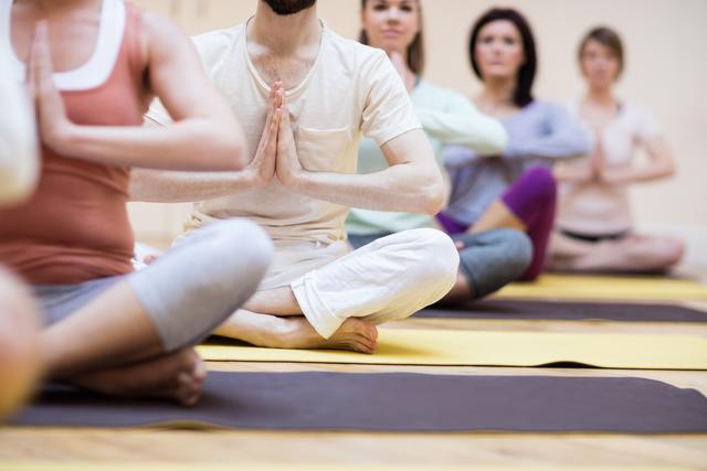 Group of individuals practicing yoga in lotus position at a fitness studio. Ideal for promoting wellness, mindfulness, fitness classes, and healthy lifestyle activities. Suitable for use in advertisements for yoga studios, fitness centers, and wellness programs.