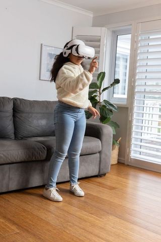 Young girl exploring virtual reality in living room wearing white vr headset and pointing