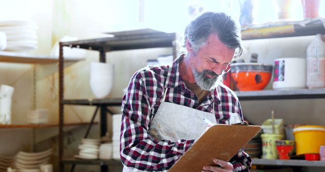 Smiling Middle-aged Man in Pottery Workshop Holding Clipboard - Download Free Stock Images Pikwizard.com