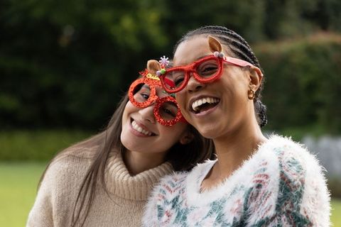 Smiling diverse friends wearing red glitter novelty glasses celebrating outdoors