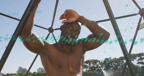 Shirtless mature man gripping geodesic dome bars, sunlit urban park strength training