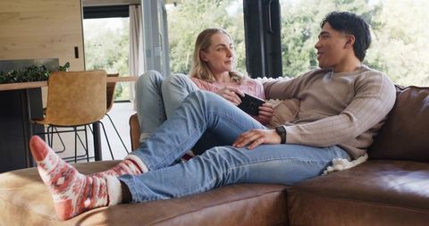 Couple relaxing on brown leather sofa wearing knit sweaters and patterned wool socks
