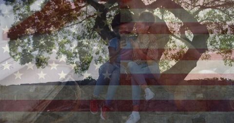Young friends sharing smartphone on park wall with faded american flag overlay
