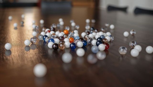 Colorful glass and opaque marbles clustering and scattering on wooden table with soft bokeh