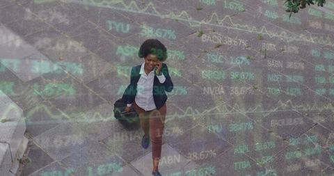 Businesswoman Walking Through Stock Market Projections with Luggage