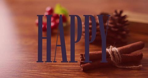Happy typography on warm rustic wood featuring cinnamon sticks, pine cone, cozy holiday
