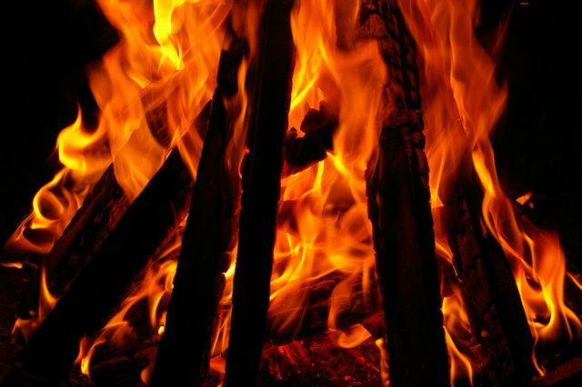 Close-up of brightly burning firewood at night, emitting strong orange flames and warmth. Useful for camping advertisements, outdoor activities promotions, warmth and coziness themes, adventure content, and wilderness tutorials.