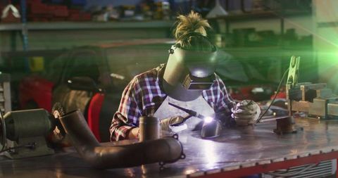 Metalworker welding curved pipe in workshop environment