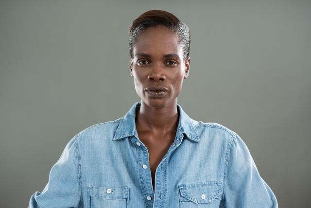 Portrait of androgynous man in denim shirt posing against grey background