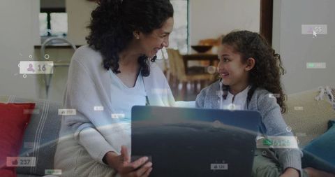 Mother and daughter bonding over laptop with social media overlays cozy living room
