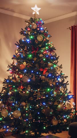 Vertical holiday video of glowing star topper and colorful lights on Christmas tree