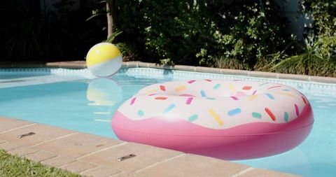 Vibrant donut pool float and beach ball in sunlit swimming pool