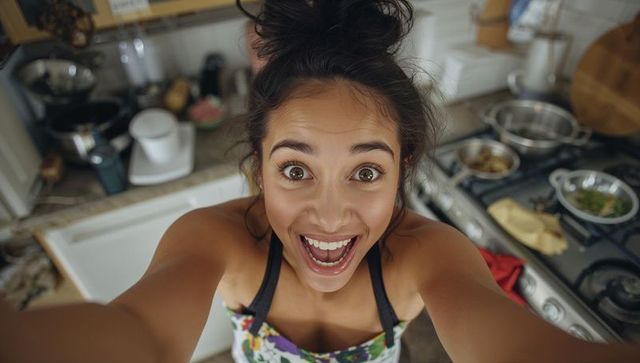 Cheerful woman excited while cooking in home kitchen
