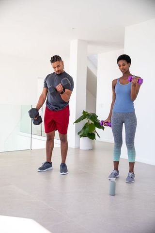 Diverse friends performing home workout with dumbbells