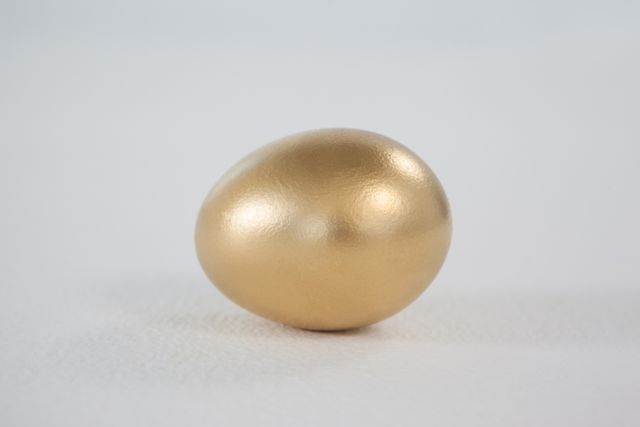 Golden Easter egg on white background, perfect for holiday-themed designs, luxury concepts, and festive decorations. Ideal for use in advertisements, greeting cards, and social media posts celebrating Easter or symbolizing wealth and opulence.