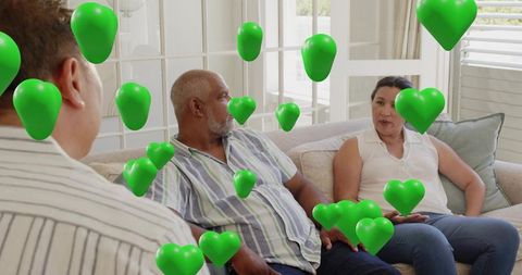Adults chatting on living room sofa with floating green hearts symbolizing support