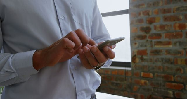 Businessman Typing on Smartphone in Office with Exposed Brick Walls - Download Free Stock Images Pikwizard.com