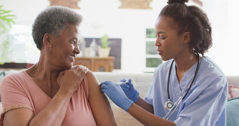 Nurse Administering Vaccine at Home Visit for Elderly Patient