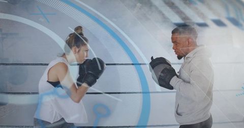 Female boxer sparring with coach holding focus mitts in ring with blue tech overlay