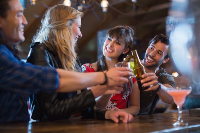 Cheerful friends toasting drinks at bar counter in pub