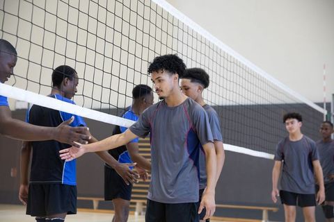 High school african american teens shaking hands across volleyball net team sportsmanship