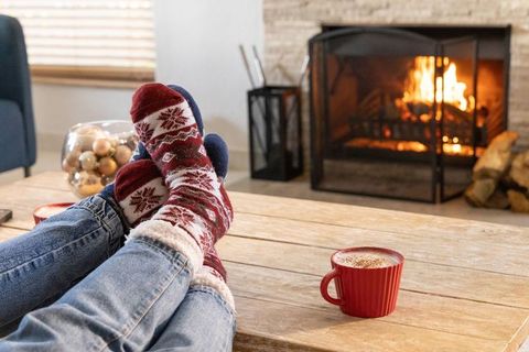 Cozy winter evening feet up by fireplace knit socks and red mug of hot cocoa