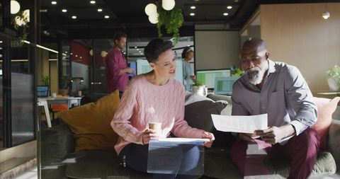 Senior Professionals Discussing Business Reports in Modern Office Lounge