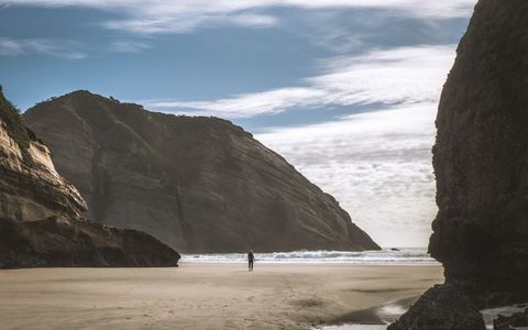 Solitary Figure Walking on Remote Sandy Beach
