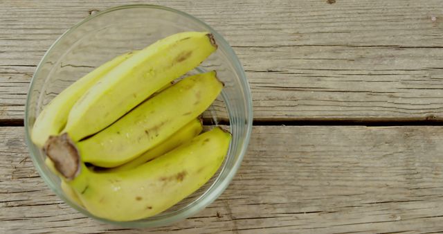 A bowl of ripe bananas sits on a rustic wooden surface, with copy space. Bananas are a nutritious snack, rich in potassium and dietary fiber.