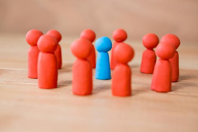 Conceptual image of blue figurine standing between a group of red figurines