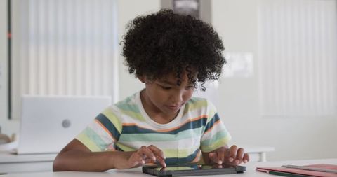 Concentrating child tapping tablet at school desk for digital learning and focused study