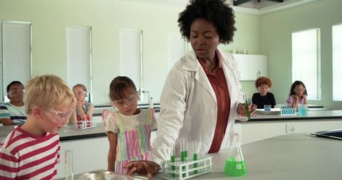 African American teacher demonstrating science experiment to elementary students in lab