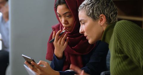 Diverse Women Collaborating on Smartphone for Serious Discussion