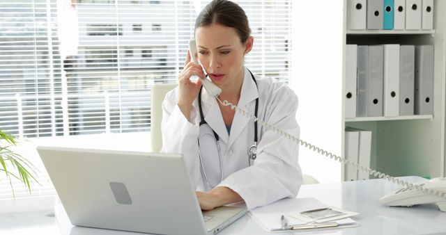 Doctor Consulting on Phone While Working on Laptop in Office - Download Free Stock Images Pikwizard.com