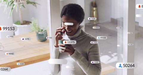 Smiling woman talking on smartphone while holding mug with floating social notifications