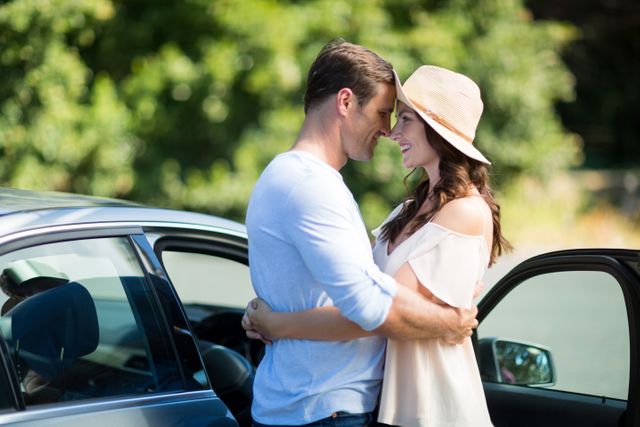 Happy young couple embracing by car on sunny day