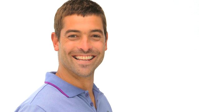 Man smiling in blue shirt against white background. Useful for advertisements, websites, blogs promoting happiness, positivity or casual lifestyle.