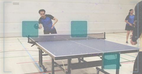 Indoor table tennis club match showing male player hitting forehand return in sports hall