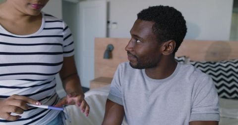Young african american couple reacting to pregnancy test in bedroom