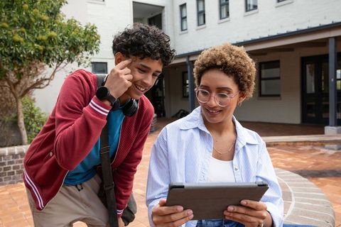 African American Teens Sharing Tablet in Courtyard Learning Together